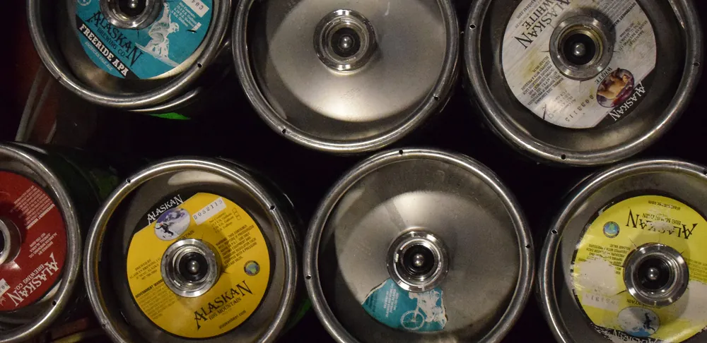 Alaskan Brewing Company 仓储区的一排不锈钢啤酒桶，桶顶可见阀口